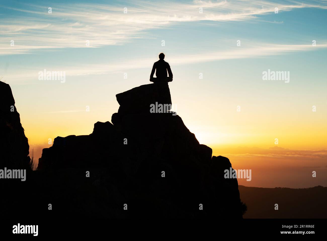 Silhouette Of Man Sitting On Top Of Mountain At Sunset Stock Photo - Alamy