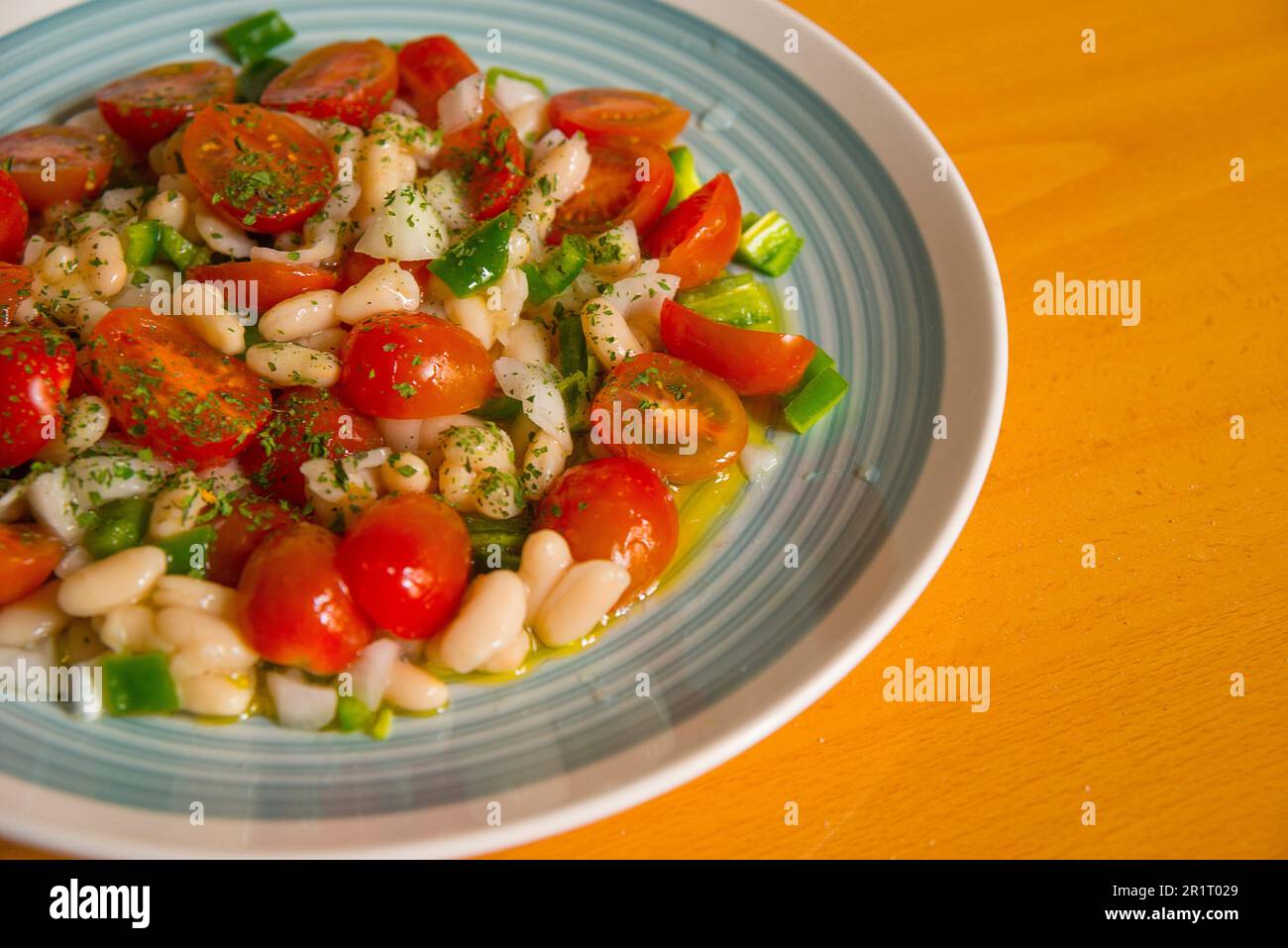 Salad made of beans, cherry tomatoes, green pepper, onion, parsley and olive oil. Stock Photo
