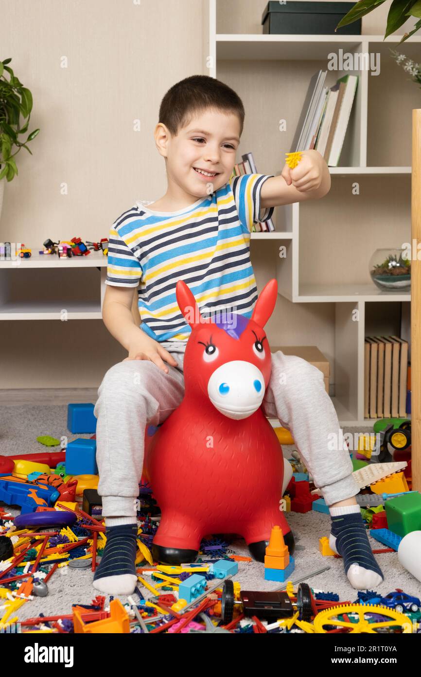 A little boy is jumping on an inflatable rubber donkey among the mess