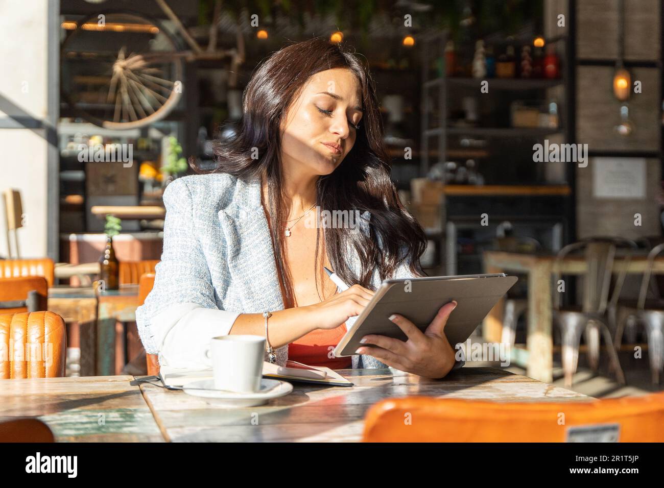 Shocked woman looking with surprise at the digital tablet while sitting in a coffee shop. Technology concept. Stock Photo