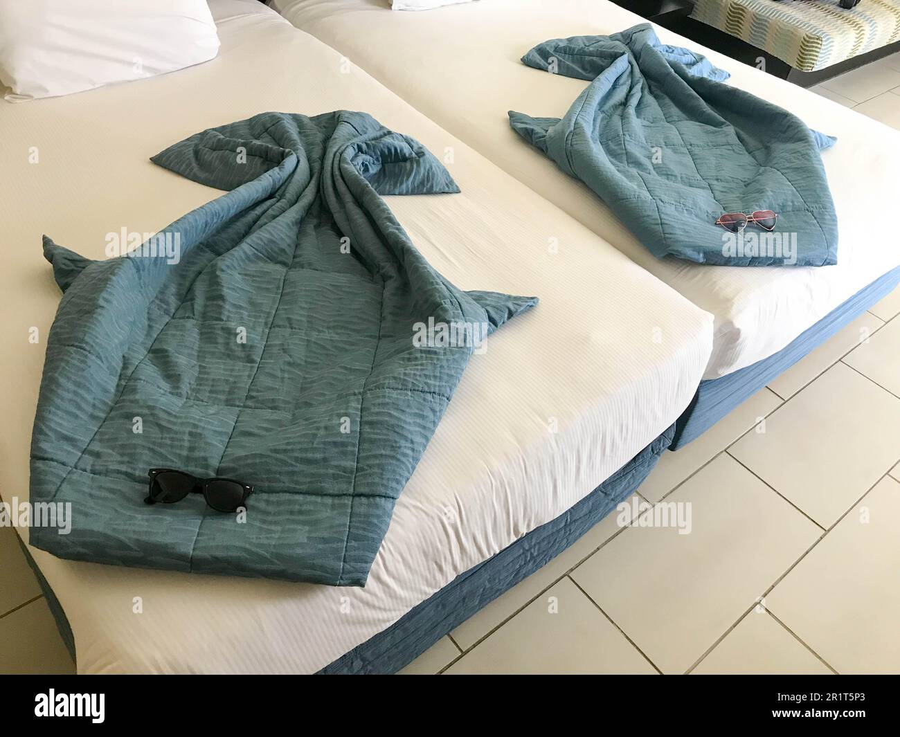 Beautiful figures of sea rays made from blankets, duvet covers on the bed with sunglasses Stock