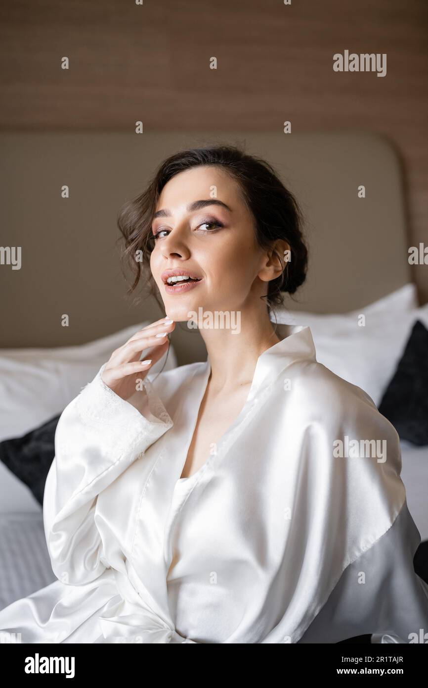 Brunette bride in a robe, posing for the camera, looking at her