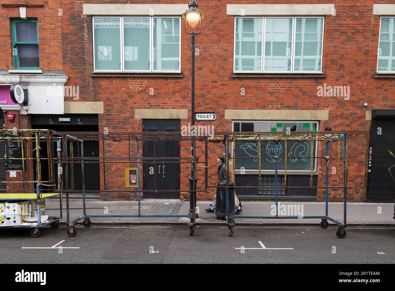 Two men walking past empty market stalls, Leather Lane Market, London ...