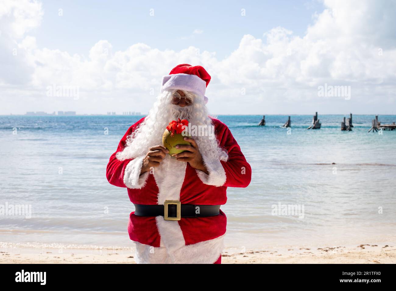 Santa Claus drinking a coconut at Isla Mujeres Mexico Beach Stock Photo