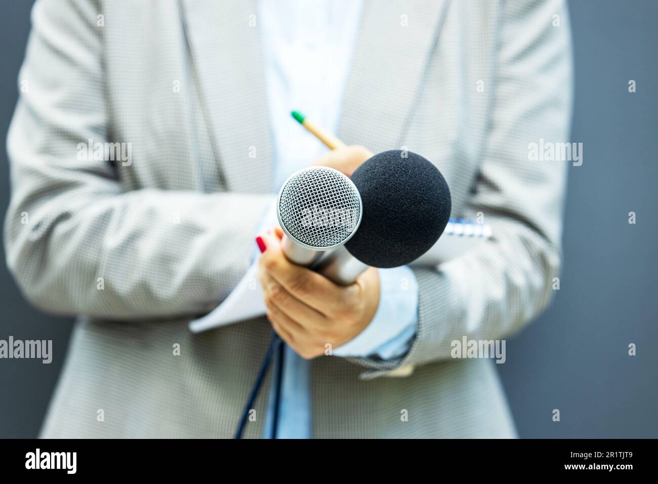 Female reporter at news conference, writing notes, holding microphone ...