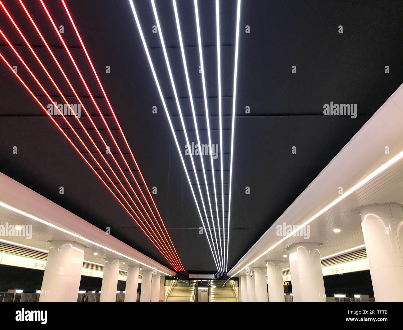 bright strips of LEDs on the ceiling. blue and white stripes, illumination. decoration of the ceiling in the subway. around white thick columns, track Stock Photo