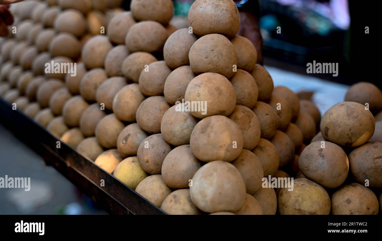 Sapota fruits stacked on one by one in fruit market to sell. Selective focus. Stock Photo