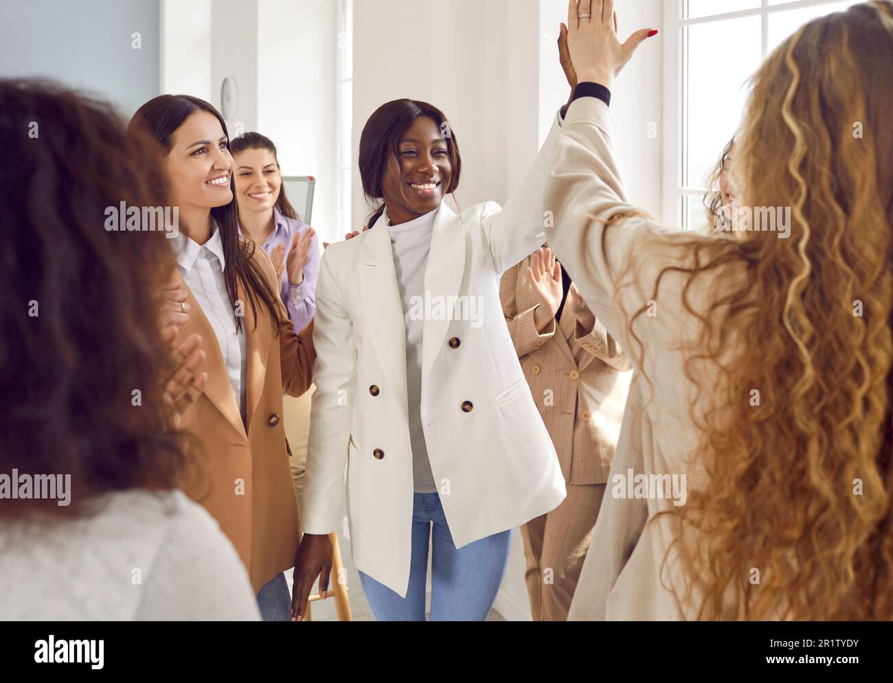 Happy women colleagues giving high five at meeting at office ...