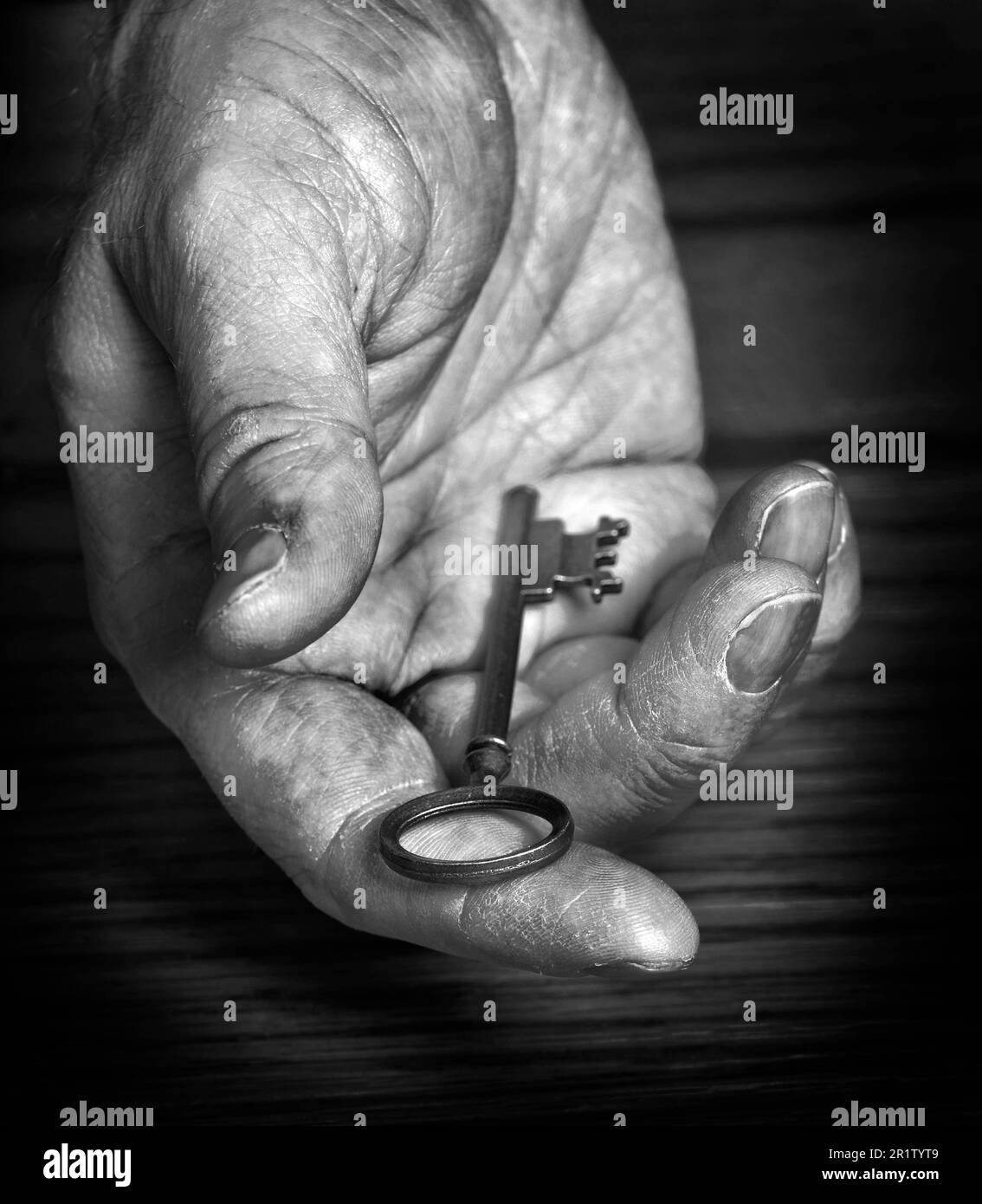 Old rough hand holding and giving away antique key to knowledge or