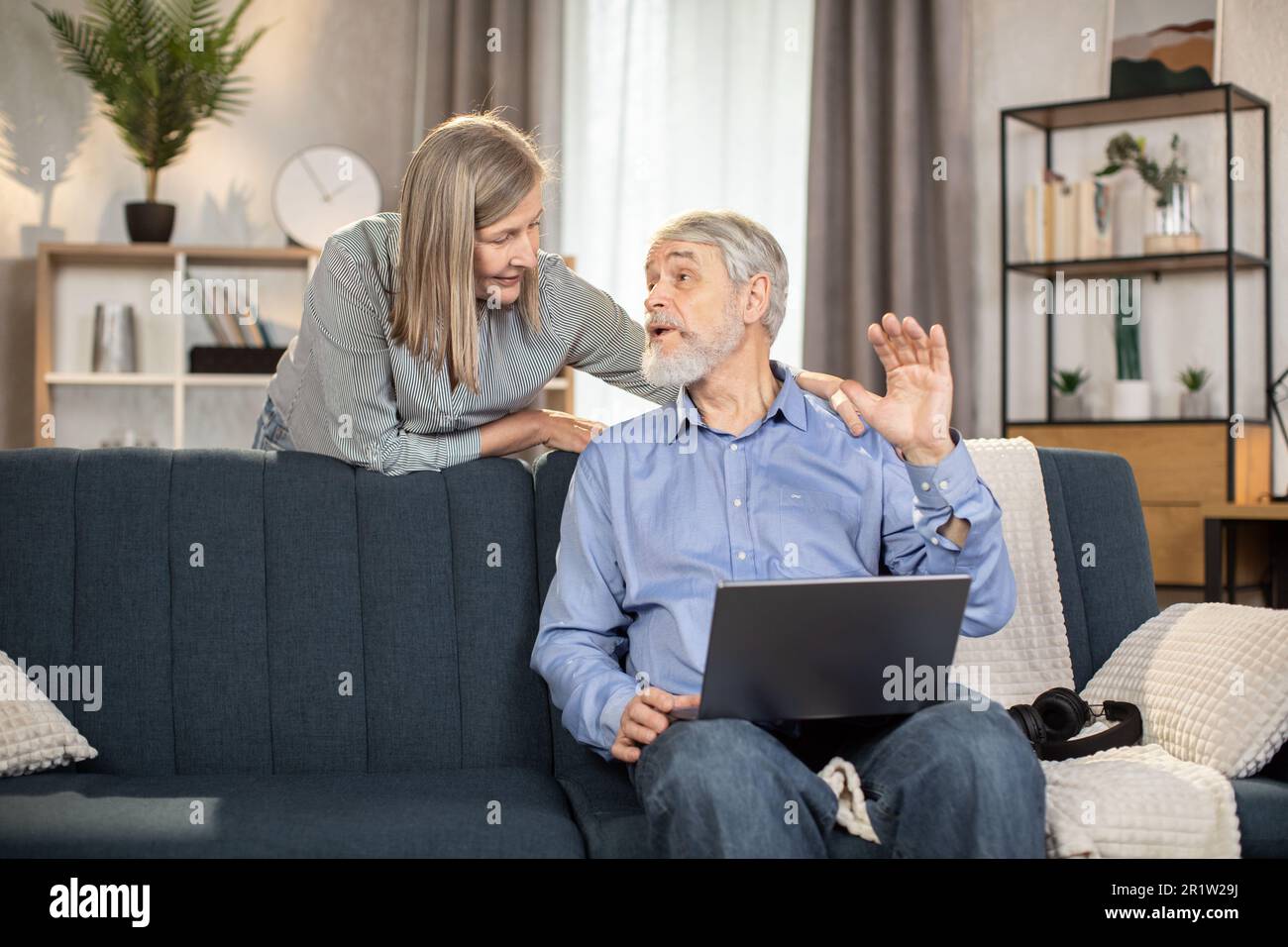 Beautiful mature lady helping senior husband with video call app on