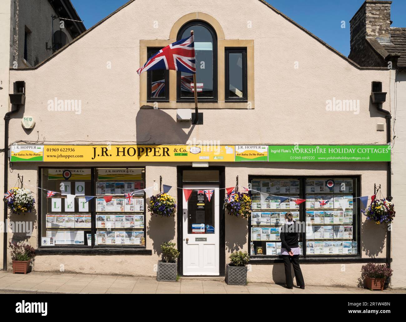 Young woman looking at J. R. Hoper, estate agents window, Leyburn