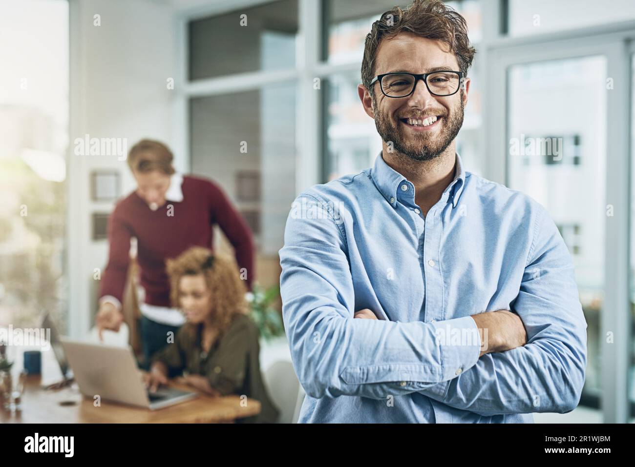 Superb managerial skills that make an impact on business. Portrait of a confident young man with his colleagues in the background at work. Stock Photo