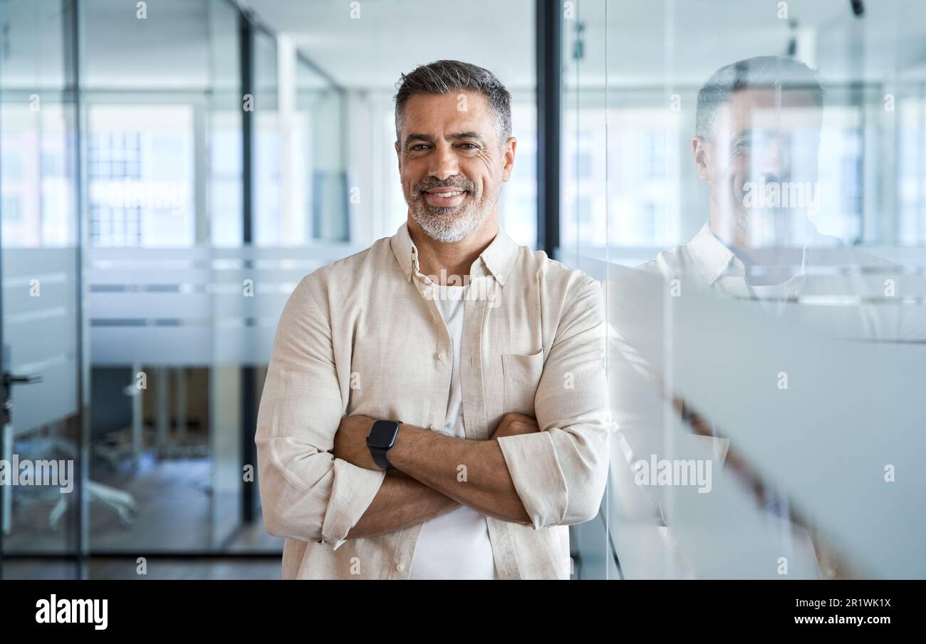 Handsome hispanic senior businessman with crossed arms smile at camera ...
