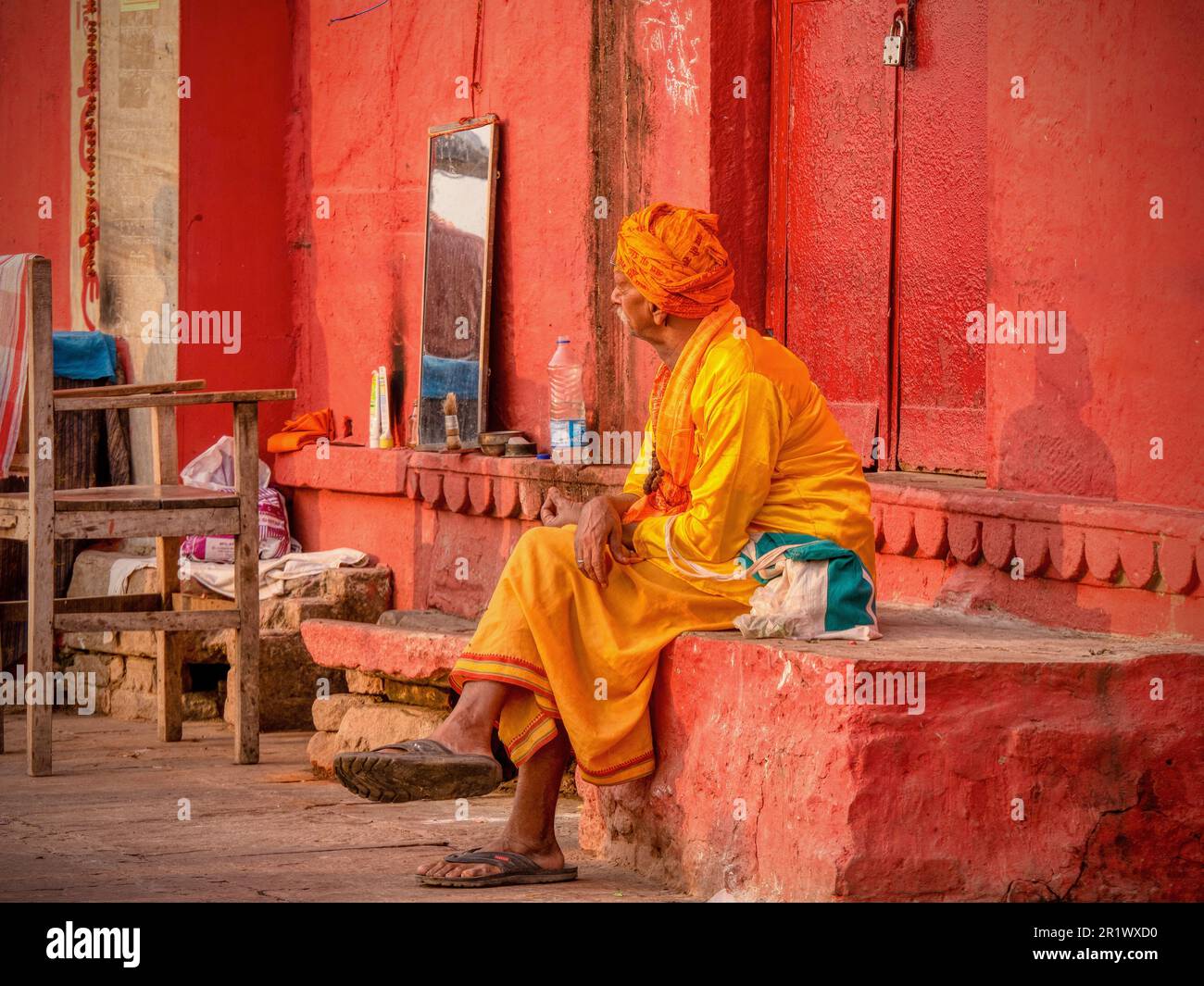 Varanasi, India - November 13, 2015. An Indian barber wearing traditional clothing waits for customers in a makeshift outdoor space. Stock Photo