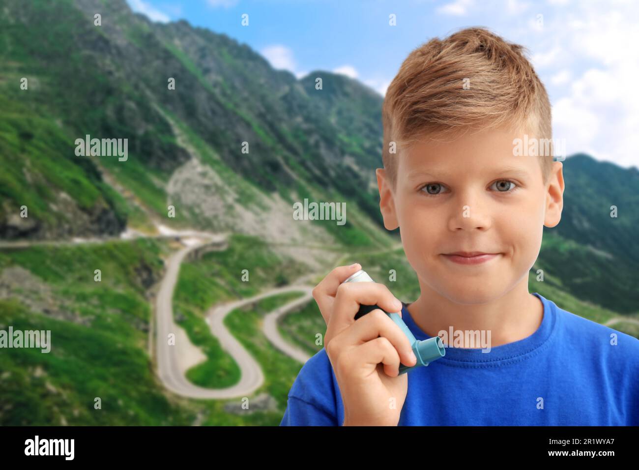Little boy with asthma inhaler in mountains on sunny day. Emergency first aid during outdoor recreation Stock Photo