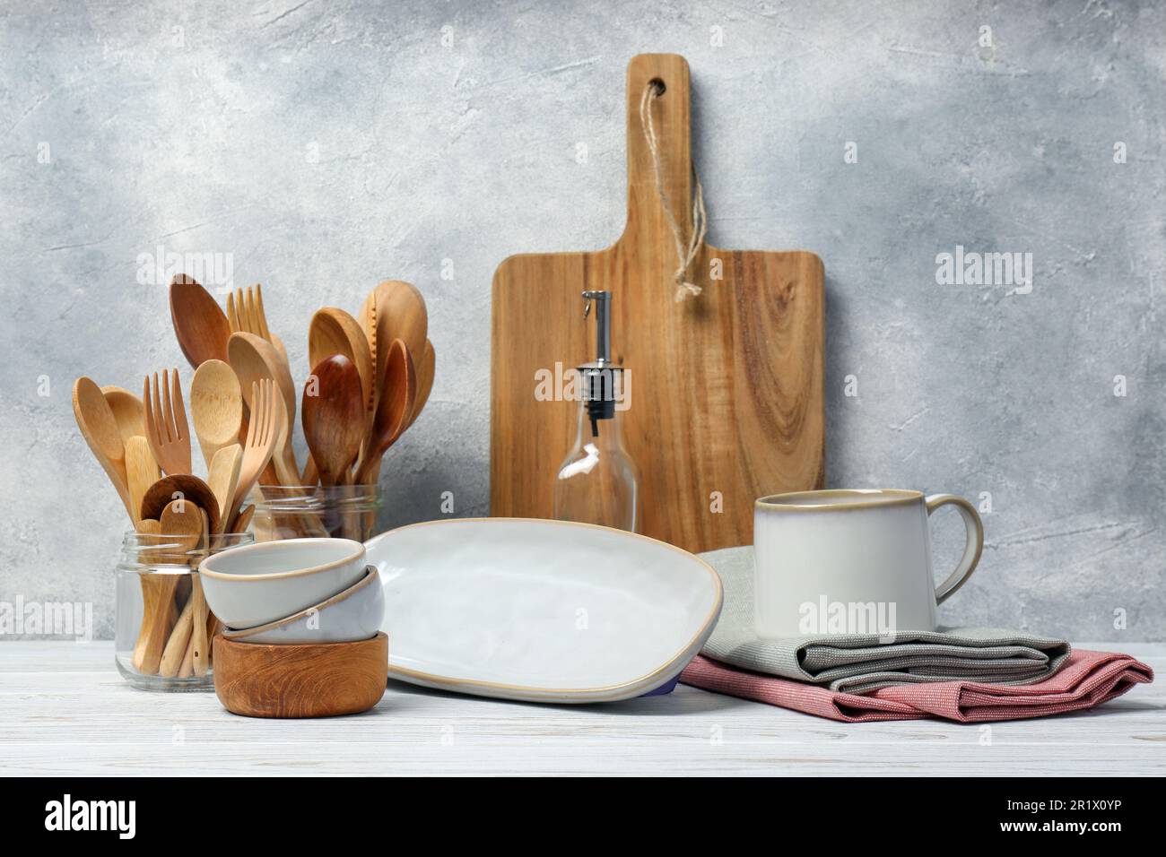 Different kitchenware and dishware on white wooden table against ...