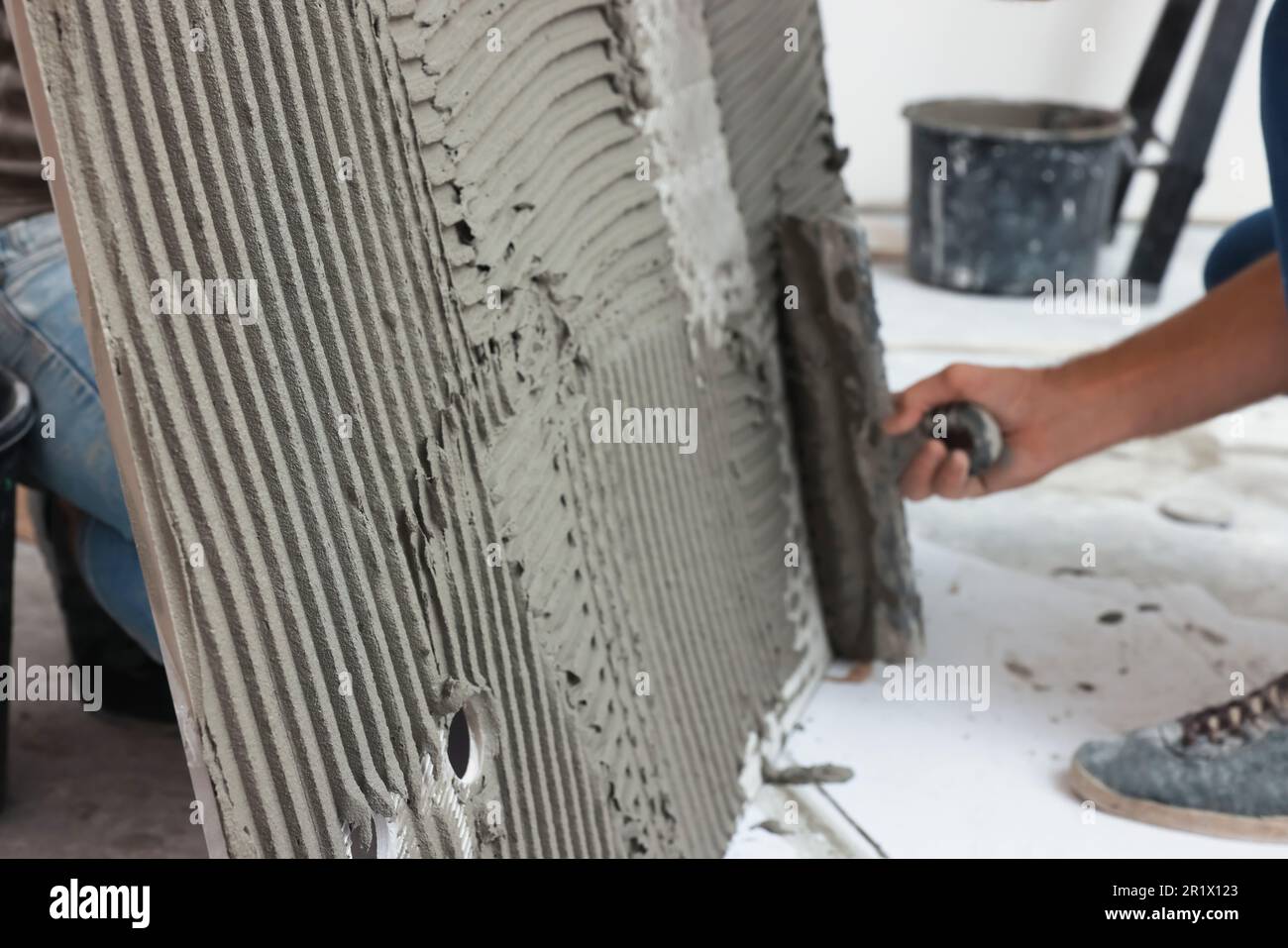 Worker spreading adhesive mix over tile with spatula, closeup Stock Photo