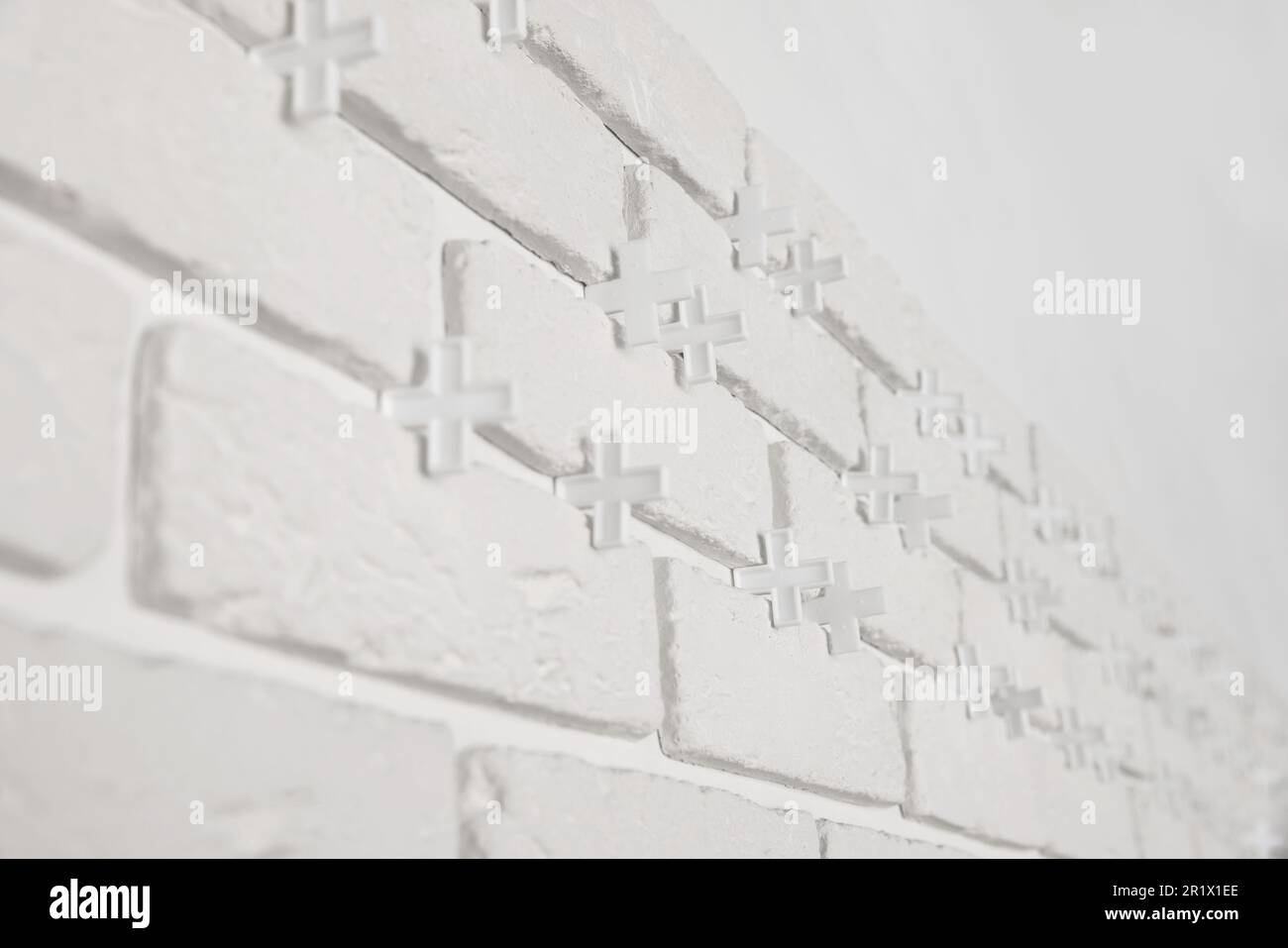 Decorative white bricks with tile leveling system on wall Stock Photo