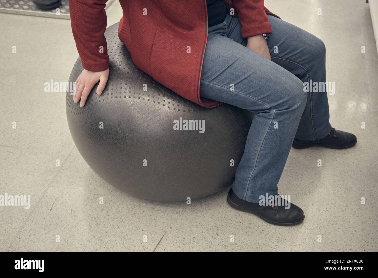 Woman in a sports store buys a black fitball. She sits on it and jumps Stock Photo