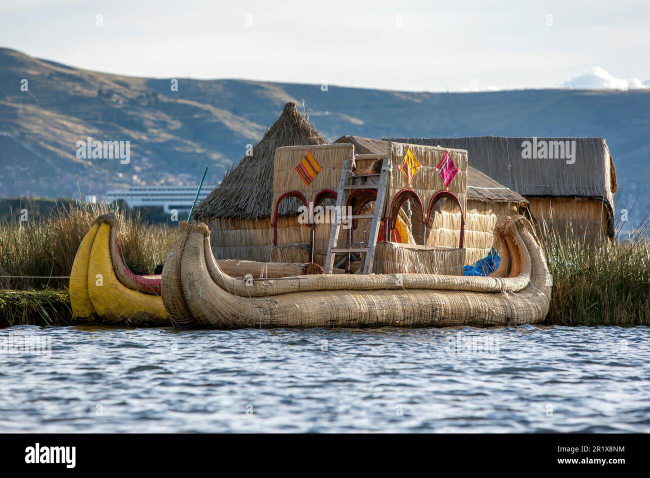 Floating reed boats, also known as balsas adjacent to one of the islands which makes up the floating reed islands of Uros on Lake Titicaca in Peru. Stock Photo