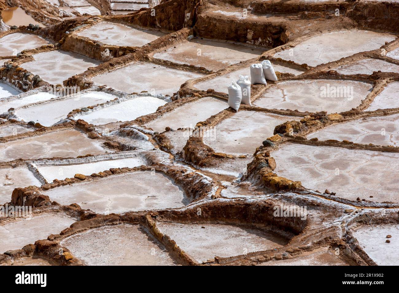 Bags of salt collected from an evaporated pond at the Maras Salt Ponds in Peru wait to be transported for sale. Stock Photo