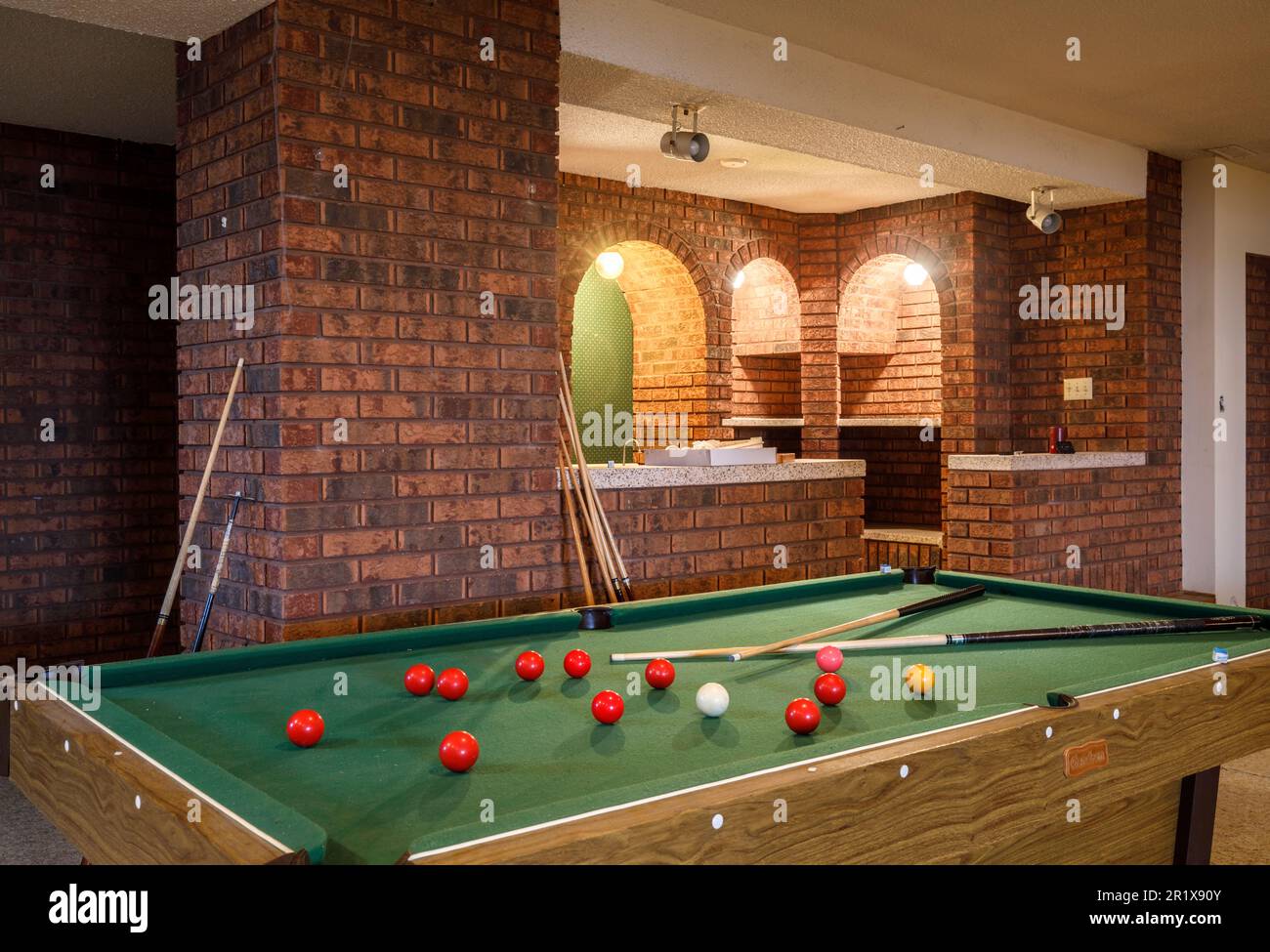 A billiards table with a home bar in the background in the basement of a large home.  This house has since been demolished. Stock Photo