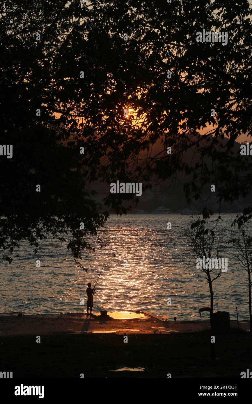 Amateur fisherman is fishing on Cengelköy Coastline at sunset in Istanbul, Turkey. Stock Photo