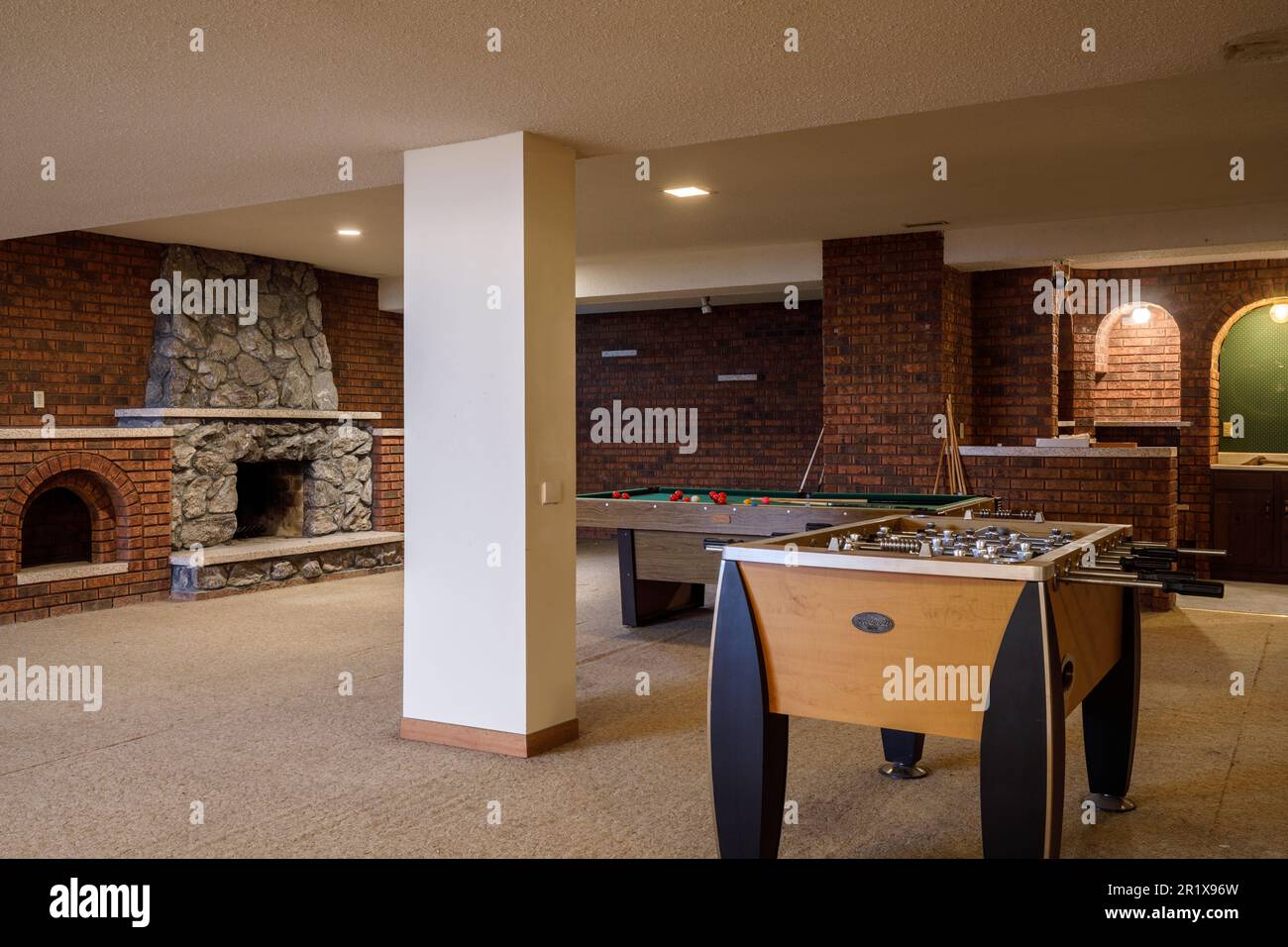 A recreation room with a foosball table, billiards table, a bar and a fireplace in the basement of a large home. This house has since been demolished Stock Photo
