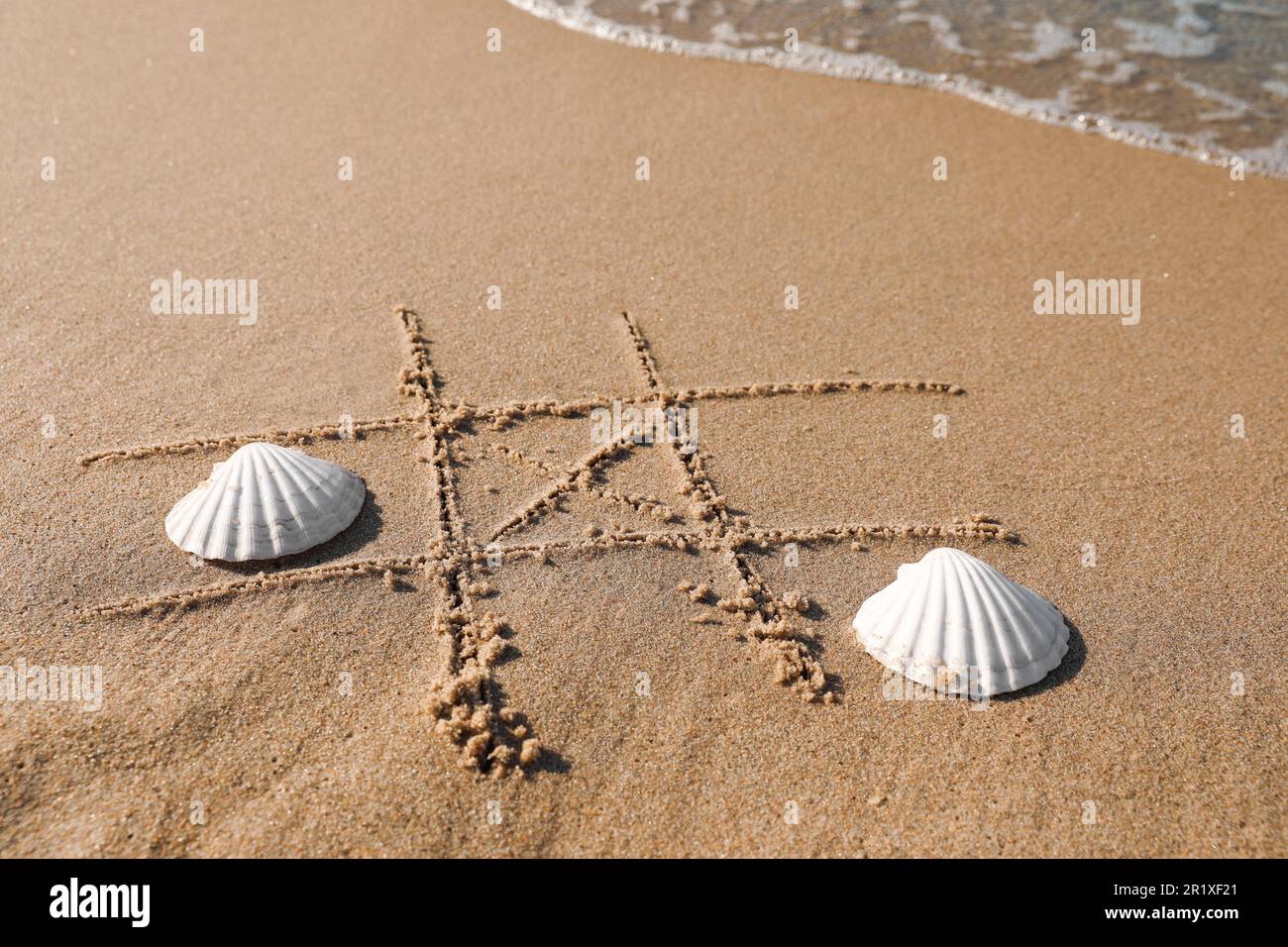 Tic Shells Playing Tic tac toe game with shells on sand near sea. Space for text ...