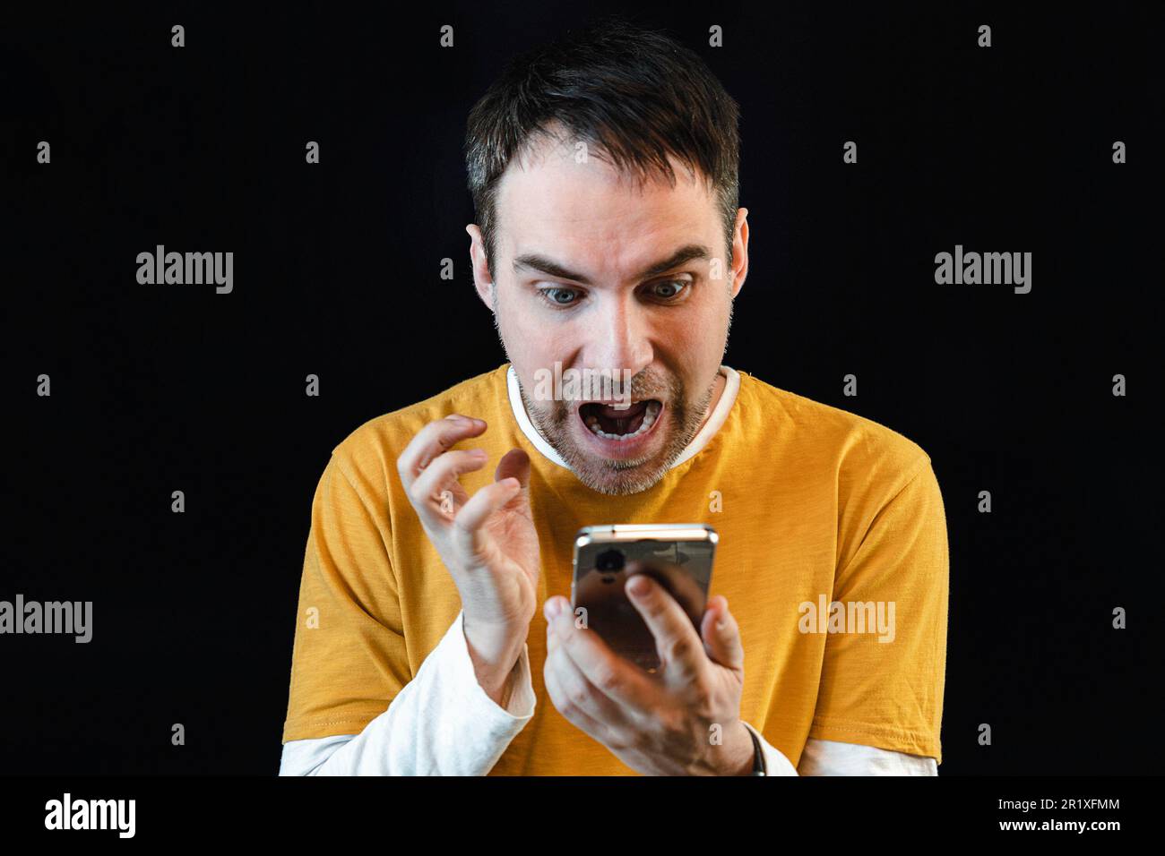 Surprised happy man holding smartphone . amazed guy reads the message on the phone. Stock Photo
