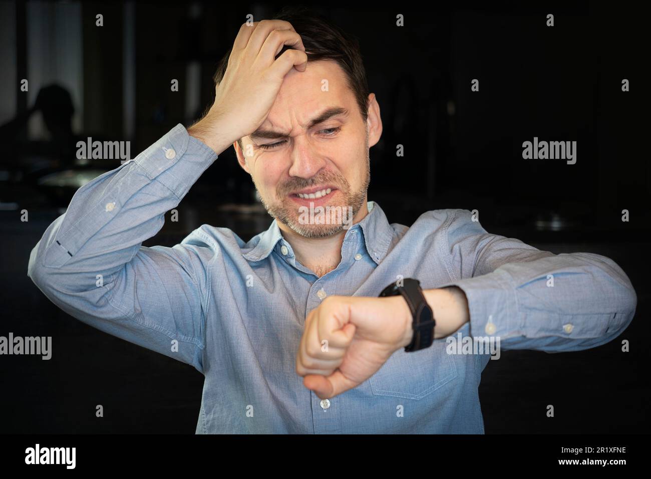 Emotional man checking time on black background. Being late concept. concept of being late for work, breaking deadlines in business, a hard deadline. Stock Photo