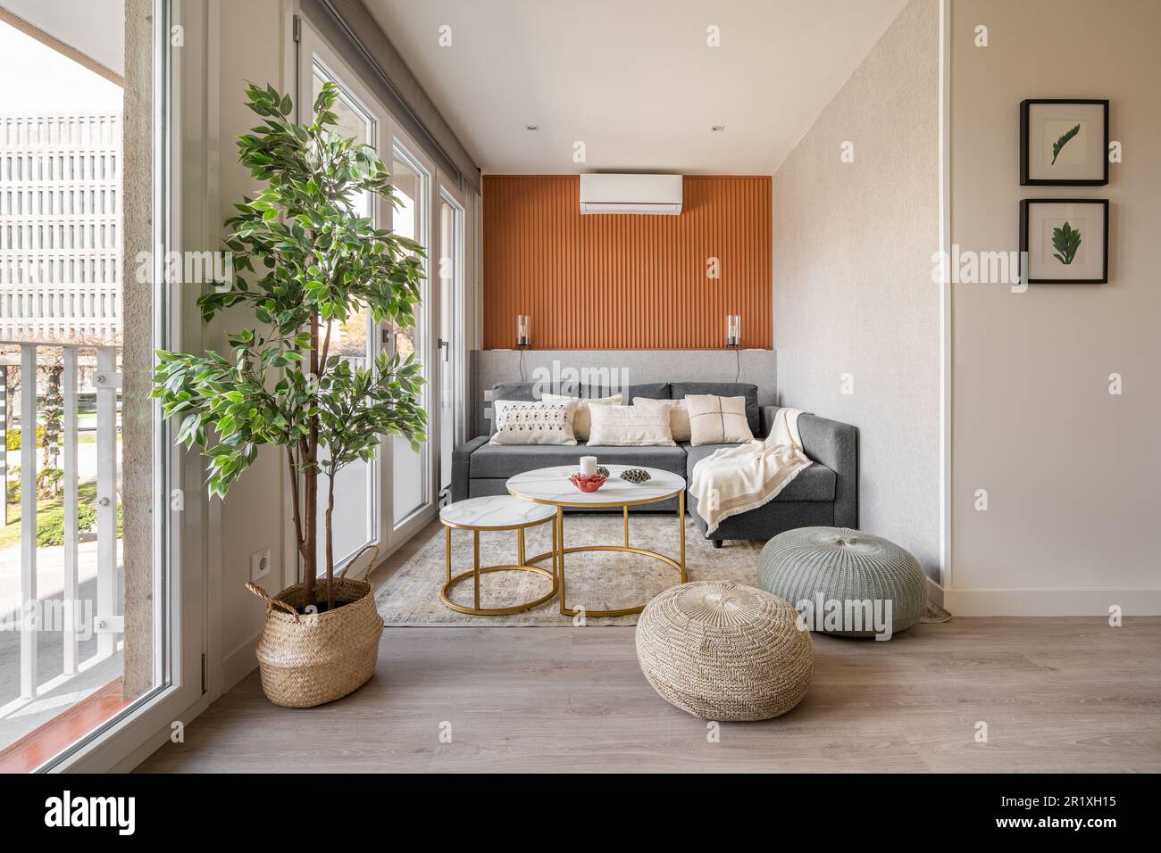 Stylish seating area with a terracotta color wall with a sofa and pouffes near the panoramic windows in the living room. The concept of a modern Stock Photo