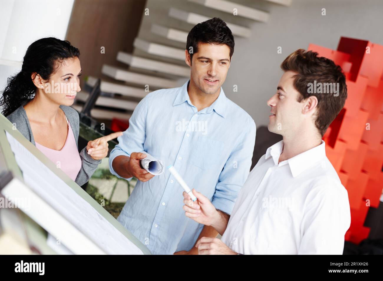 Sharing architectural ideas. Three talented architects discussing how they improve upon their blueprints. Stock Photo