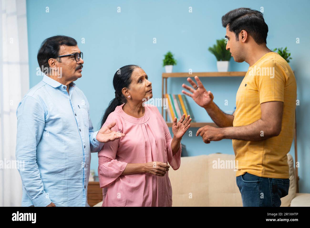 angry Indian adult son arguing with elderly senior parents at home - concept of irresponsibility, family problems and generation gap Stock Photo