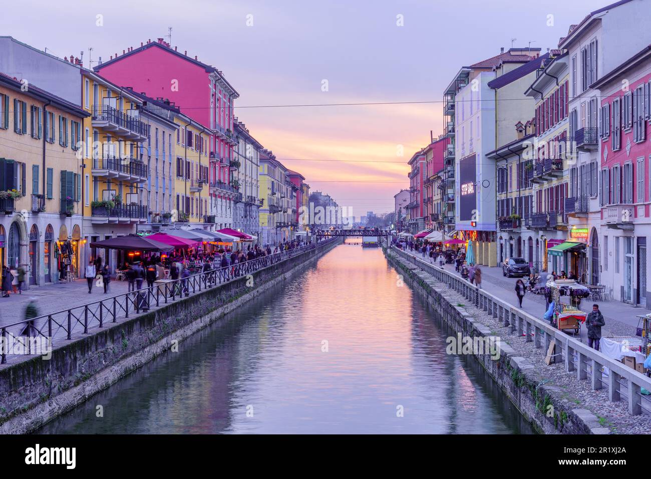 Milan, Italy - March 02, 2022: Sunset view of the Naviglio Grande canal, with locals and visitors, in Navigli, Milan, Lombardy, Northern Italy Stock Photo