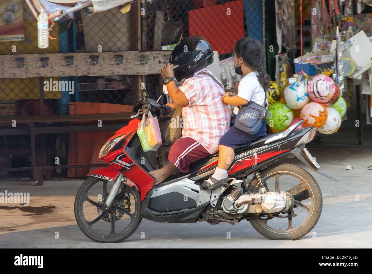 SAMUT PRAKAN, THAILAND, MAR 03 2023, A couple of small stature people ride a motorcycle Stock Photo