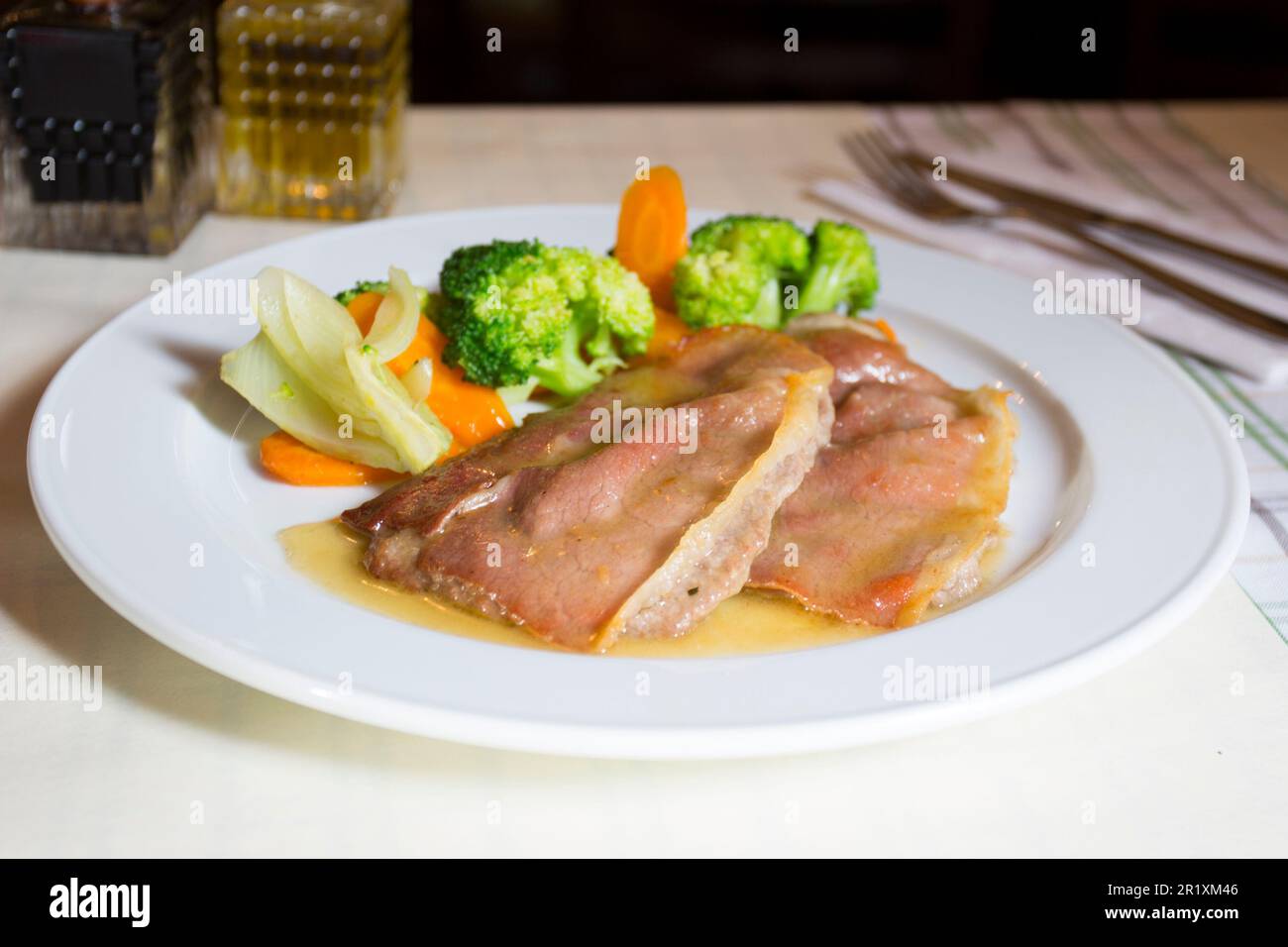 Pork loin covered with bacon and served with vegetables such as broccoli or carrots. Stock Photo