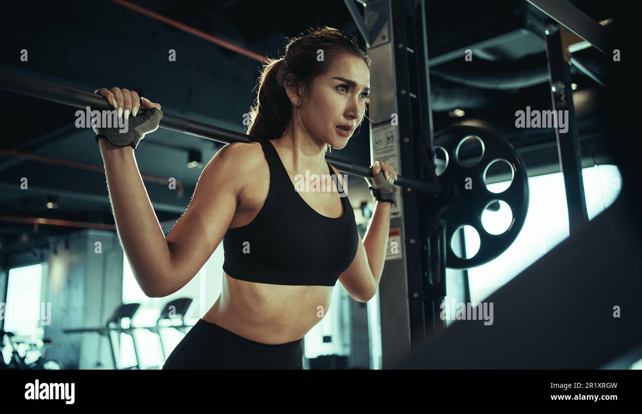 Sporty woman exercising with weight plate in the gym. Stock Photo