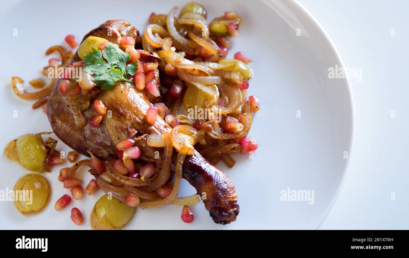 Duck confit with onion, pomegranate and grapes. Stock Photo