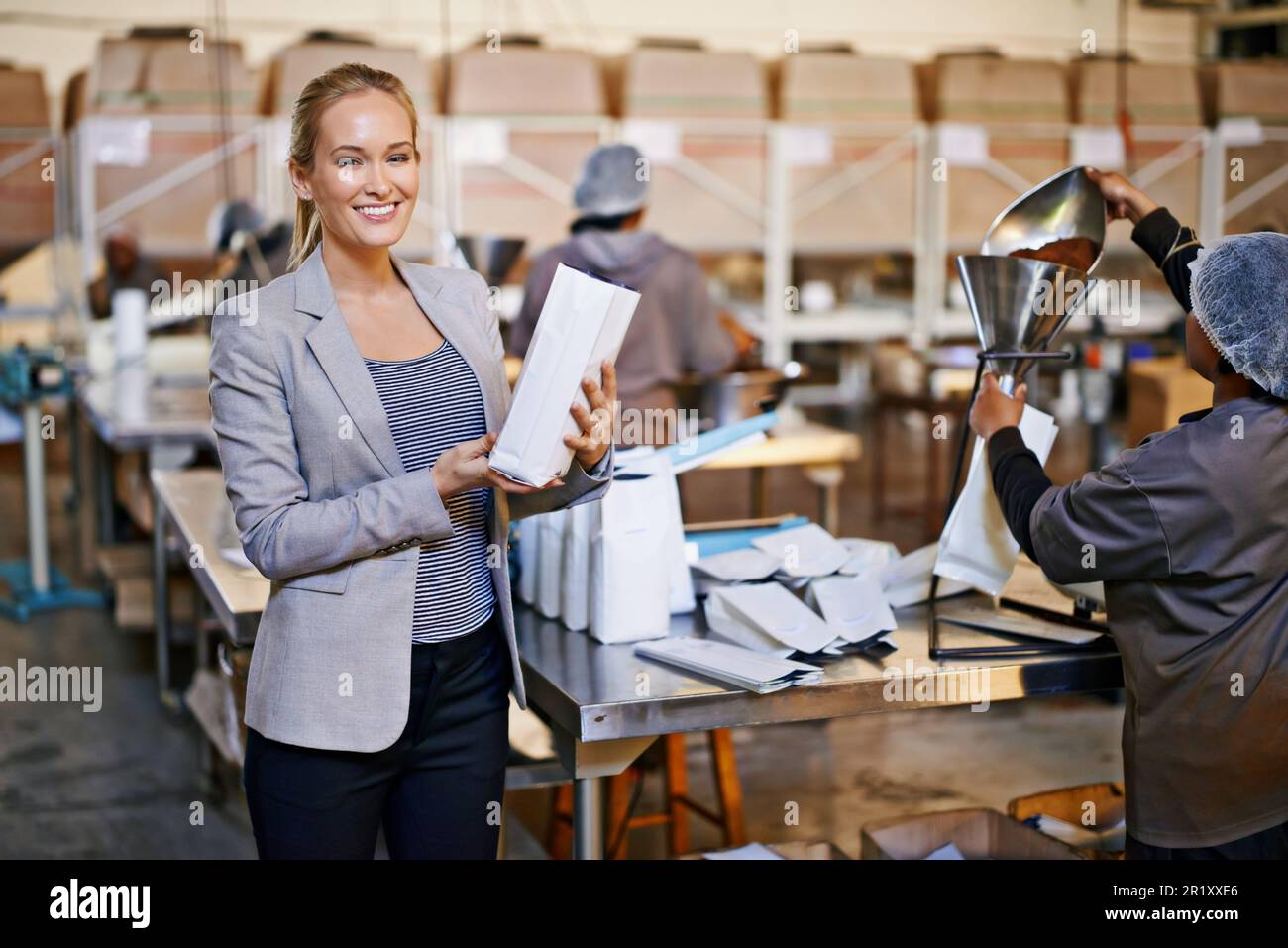 Soon to be the perfect cup of coffee. Portrait of a manager in a warehouse with workers in the background. Stock Photo