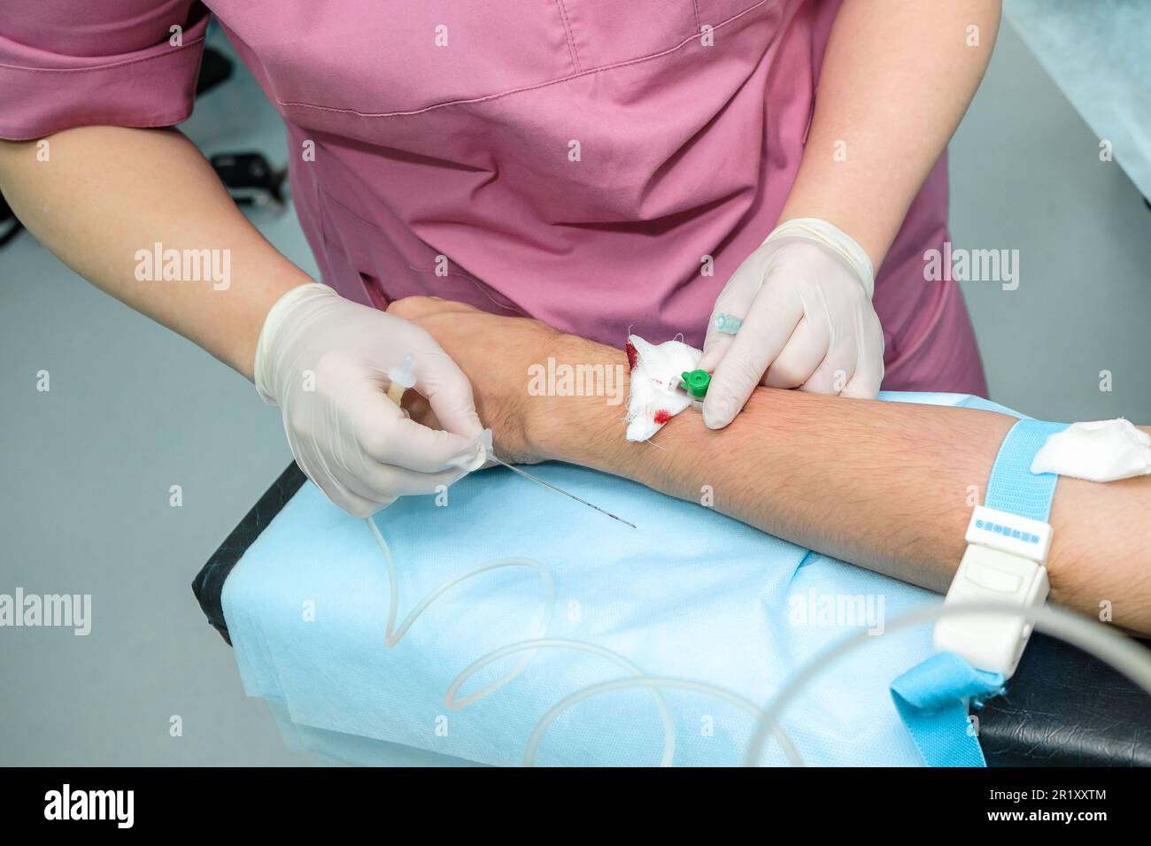 The nurse inserts a long needle into the patient's arm. Installation of
