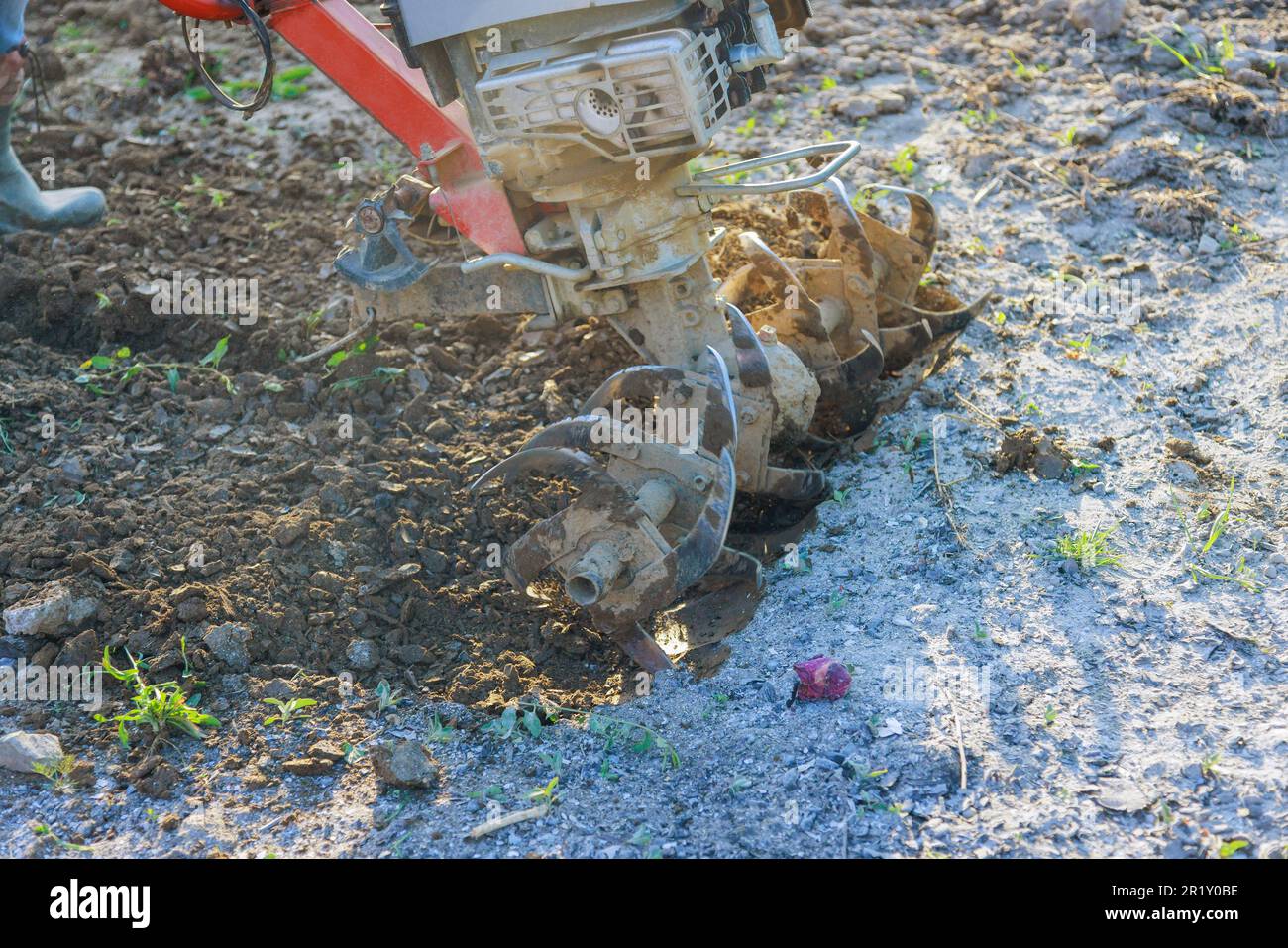 Farmer plowing land with using tiller block cultivator machinery for soil cultivation in garden