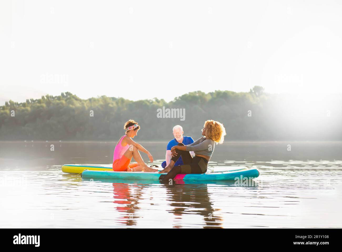 Diverse friends bonding on SUP boards: A day of relaxation and joy Stock Photo