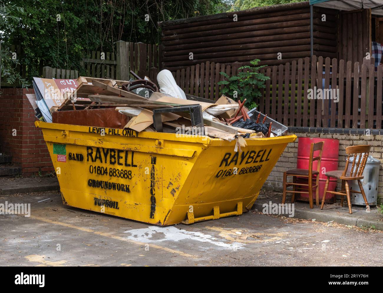 Yellow Raybell rubbish skip filled to overflowing, Stoke Bruerne, Northamptonshire, UK Stock Photo