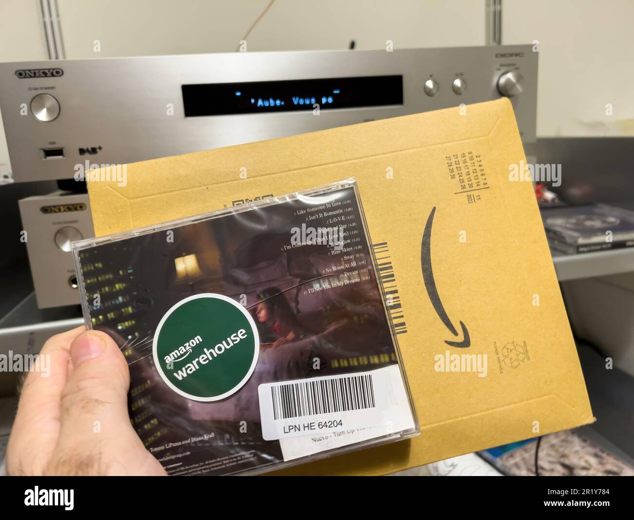 Paris, France - Dec 16, 2022: A man holds a damaged compact audio disk, the latest release from Diana Krall. The damage occurred during transport by Amazon in its cardboard package Stock Photo
