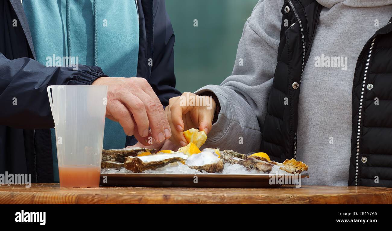 Eating oysters at a street food market, womens hands holding an oyster
