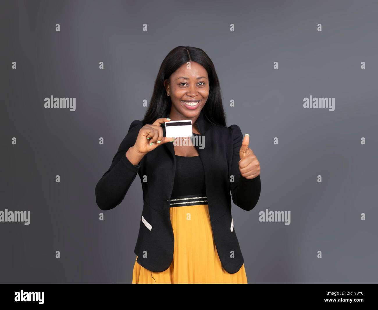 Attractive black businesswoman holding up credit card Stock Photo