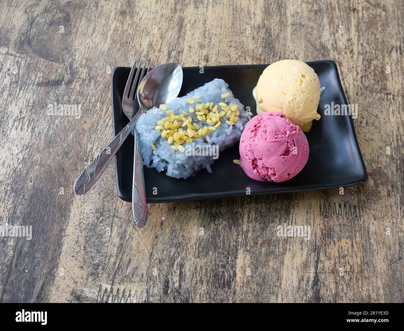 Mulberry and passion fruit ice cream with blue glutinous rice steamed with butterfly pea flowers, Two red and yellow ice creams with spoon and fork Stock Photo
