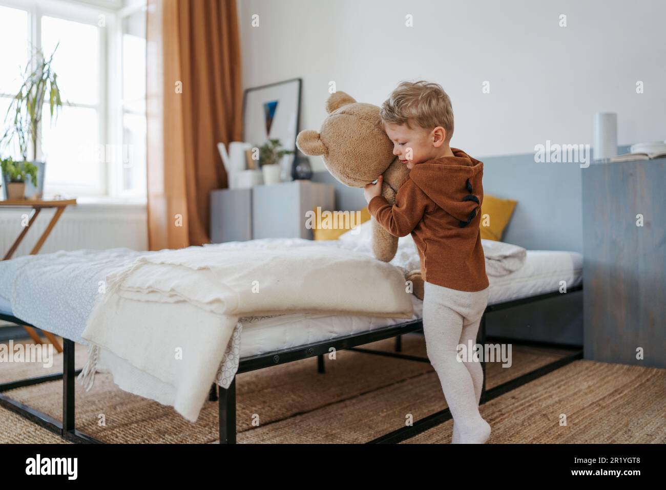 Little boy cuddling with bear toy in bedroom. Stock Photo