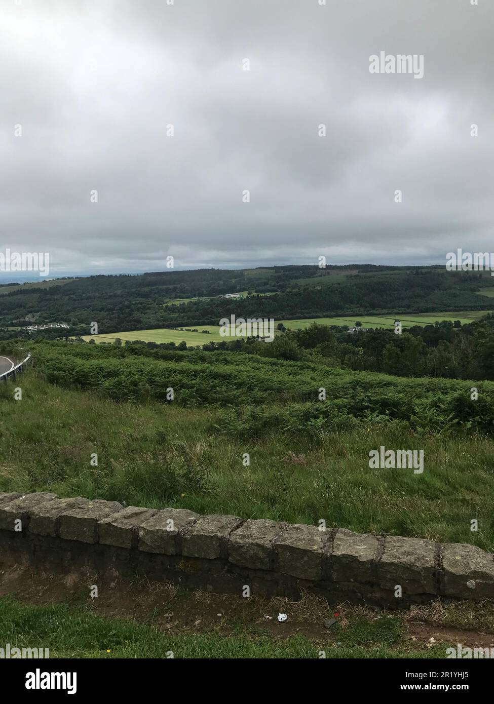 The scenic view of the lush green countryside on a cloudy day from the top of a hill Stock Photo